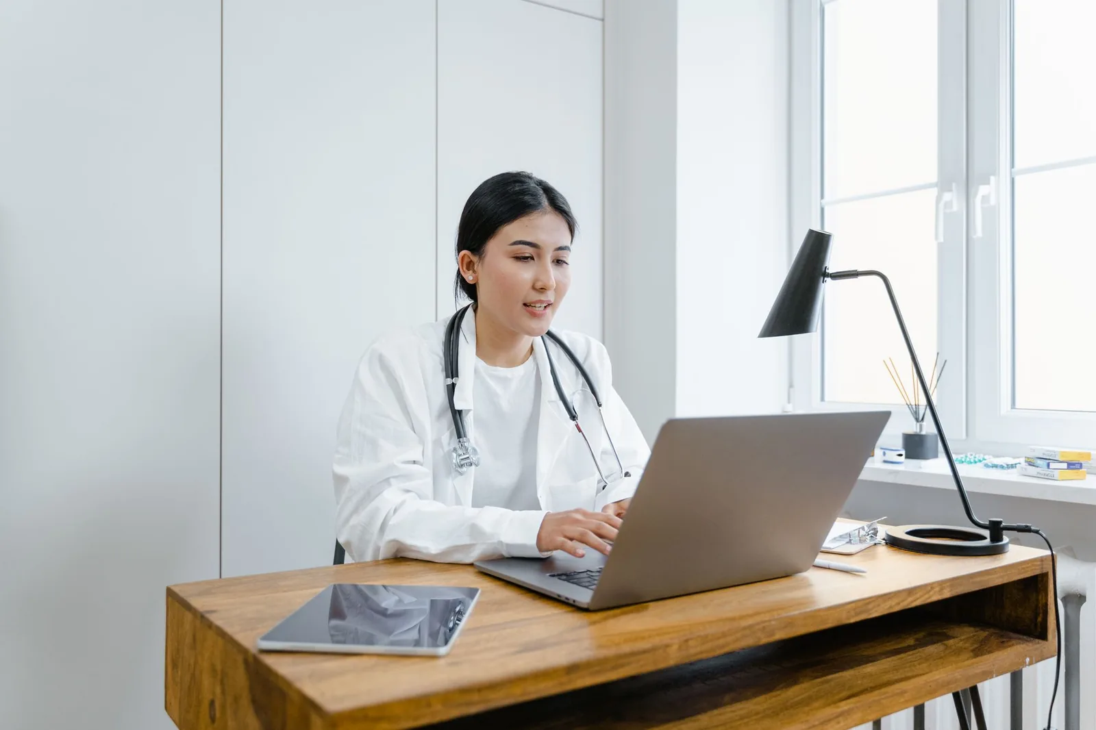 Bác sĩ đọc thông tin trên máy tính trong phòng làm việc sáng