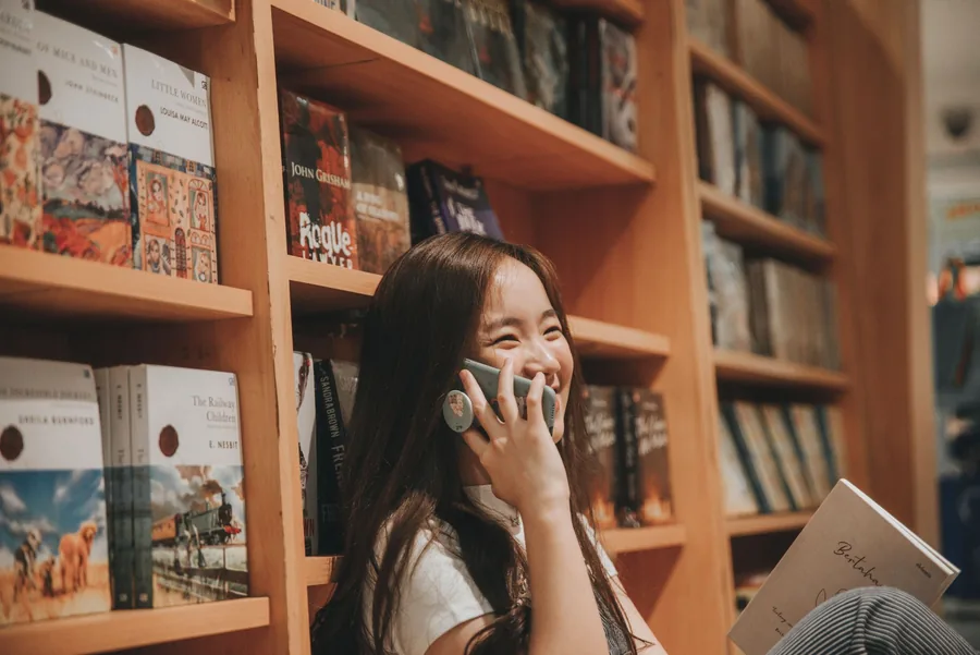 Cô gái mỉm cười khi nghe điện thoại trong thư viện